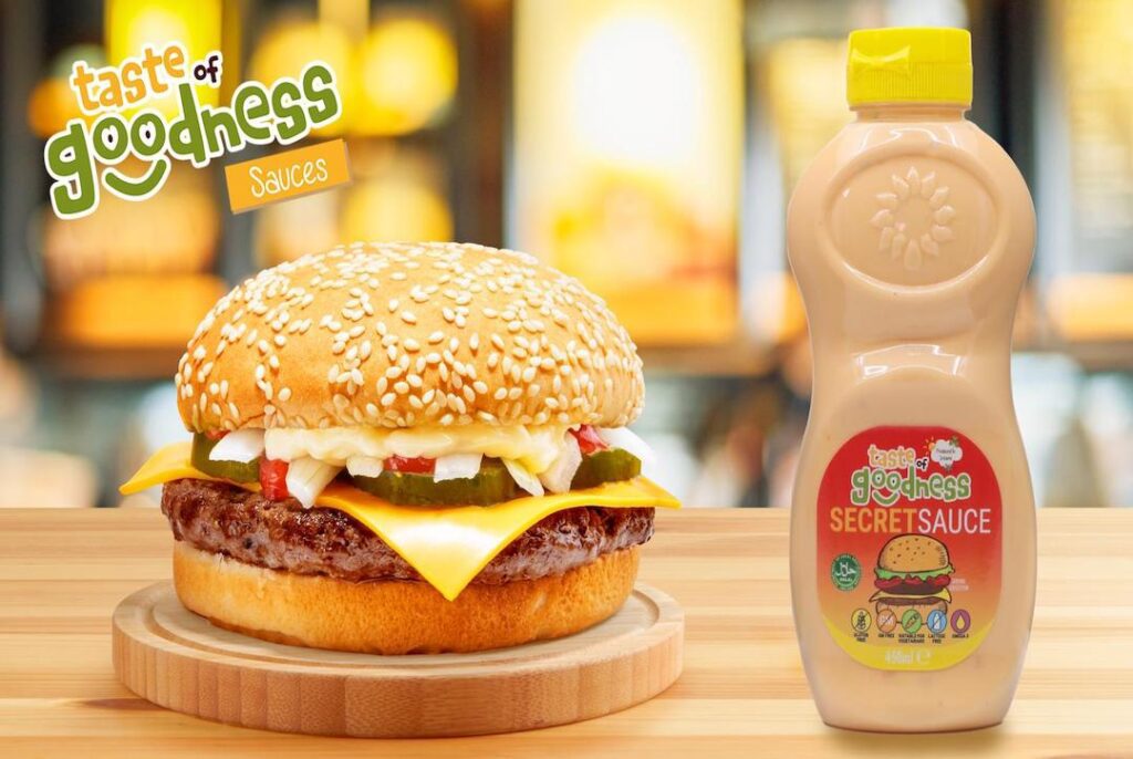 Bottle of taste of goodness secret sauce with burger to the left