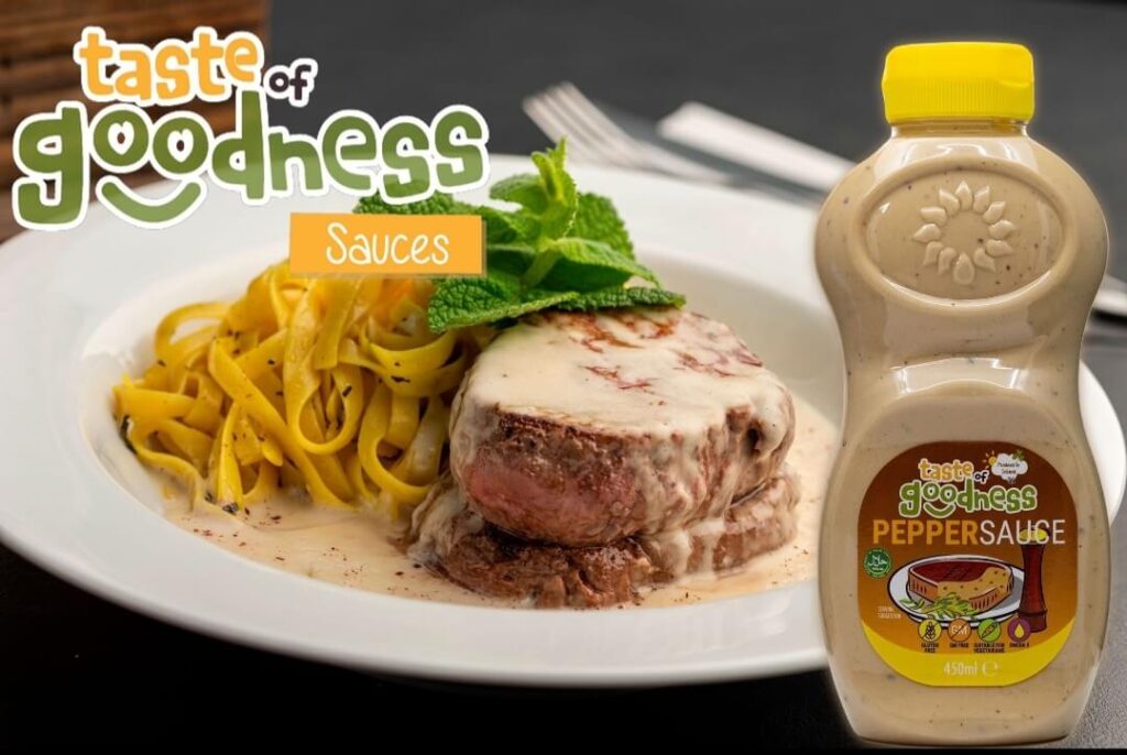 bottle of taste of goodness pepper sauce with plate of steak and pasta as the background
